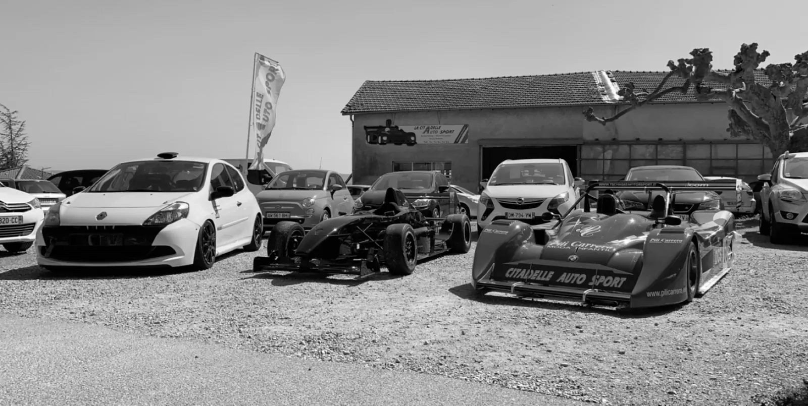 Voitures de course et de rallye devant l'ancien atelier de La Citadelle Auto Sport
